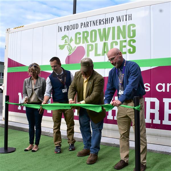 four people cut ceremonial green ribbon outdoors